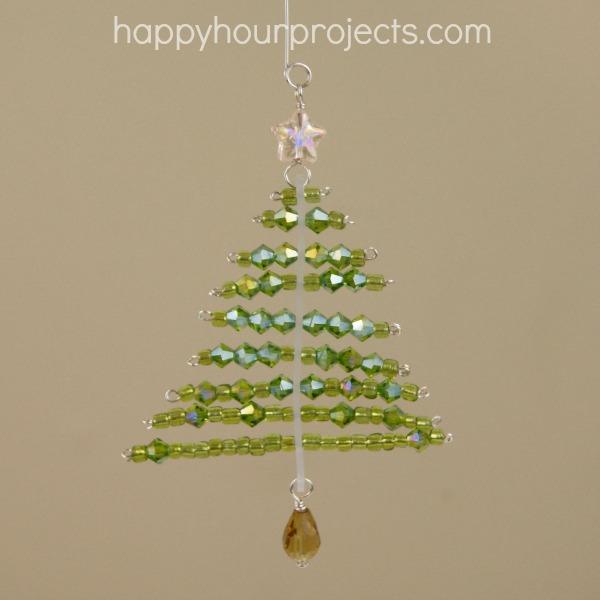 A beaded tree ornament of green glass beads in wire rows with a star bead on top and an amber drop bead at the base