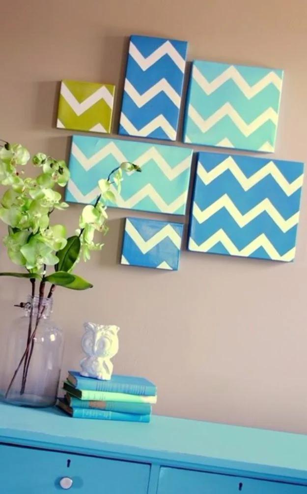 Seven square panels covered in blue, green and cream chevron paper, hung in an offset cluster on a wall