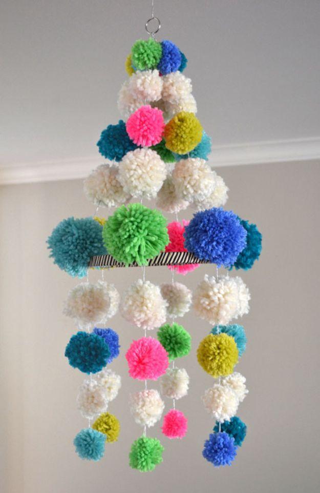 DIY baby shower decoration pom pom chandelier in cream teal blue and pink yarn pom poms hanging from a ceiling hook