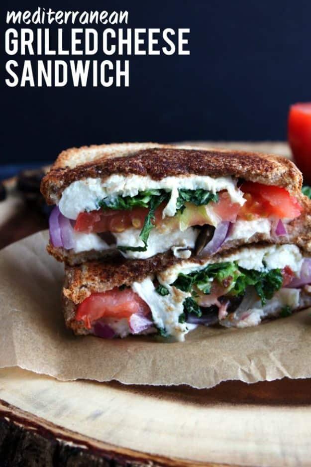 Mediterranean grilled cheese sandwich cut open showing feta, kale, red onion, tomato and black olives