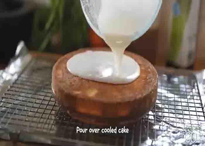 Drizzling the frosting over the lemon olive oil cake
