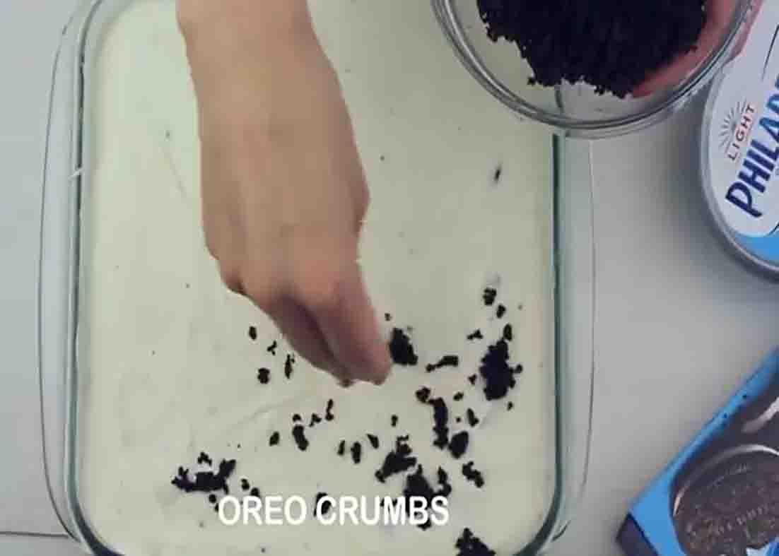 Sprinkling Oreo crumbs all over the frozen oreo dessert