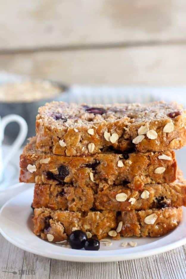 Blueberry oatmeal bread cut into thick slices and stacked on a white plate, oats and dark berries in the crumb