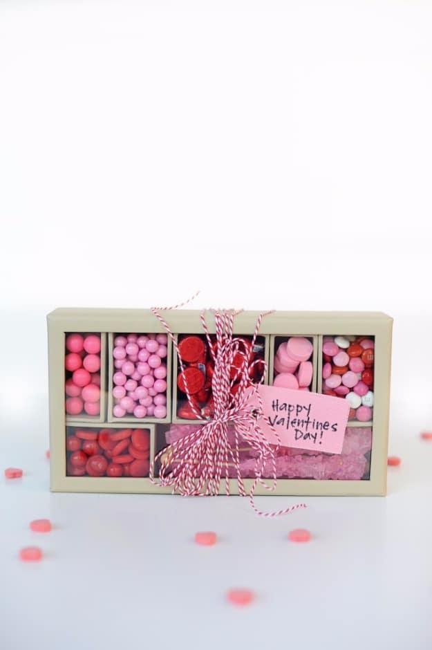 Handmade pink and red candy box filled with chocolates and colorful treats for Valentine's Day on a craft table