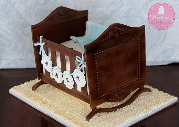 Cake carved and colored to look like a dark wood antique rocking cradle with white fondant bedding inside