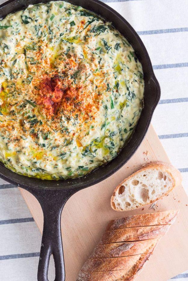 Vegan spinach dip in a cast iron skillet, dusted with paprika, served with sliced baguette alongside