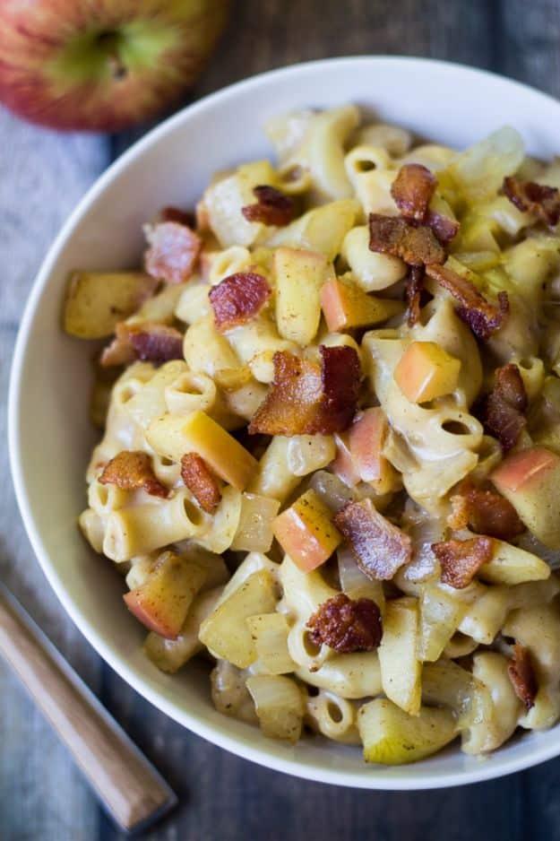 Apple bacon mac and cheese in a white bowl with visible chunks of cooked apple and crisp bacon through elbows