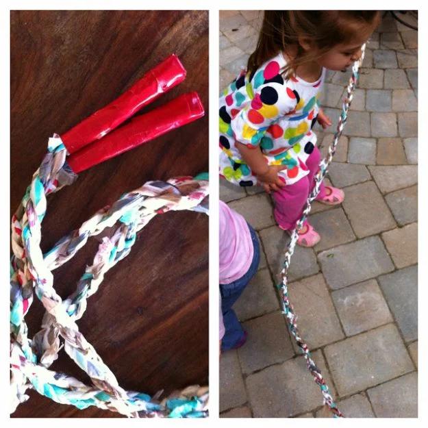 Braided plastic bag jump rope with red taped handles on a table, beside a toddler swinging the rope on a patio