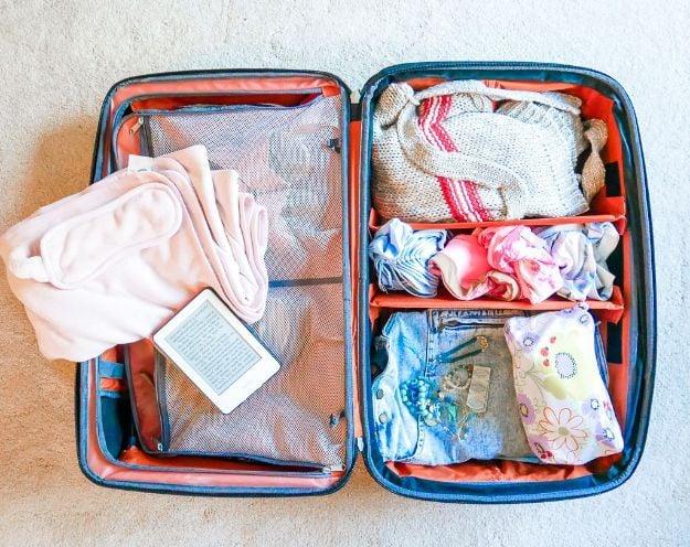 Open blue and orange suitcase with mesh packing cubes and folded clothes in both halves, plus a tablet