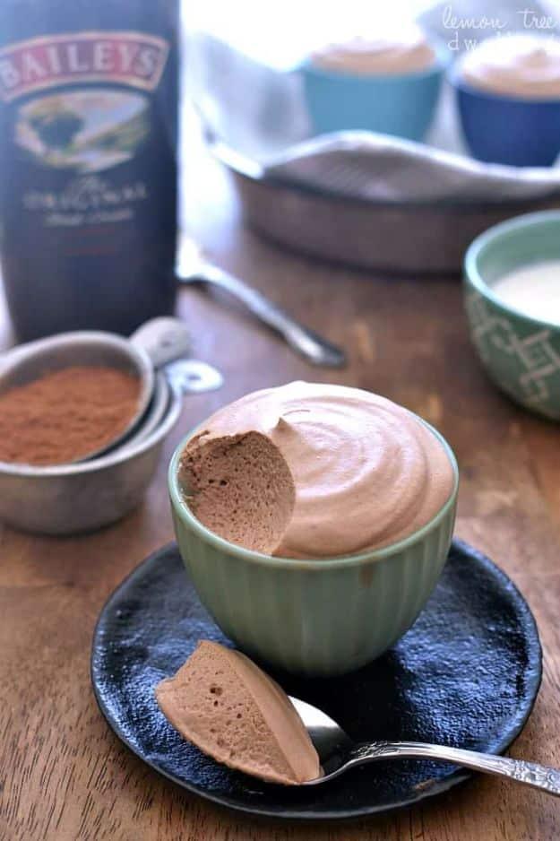 Baileys chocolate mousse swirled into a green bowl with a spoonful beside it and the bottle behind on wood
