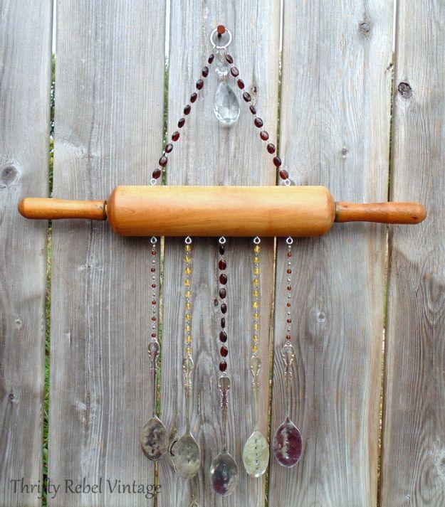 A vintage wooden rolling pin lettered in black hangs from a ribbon on a kitchen wall above a run of open shelving