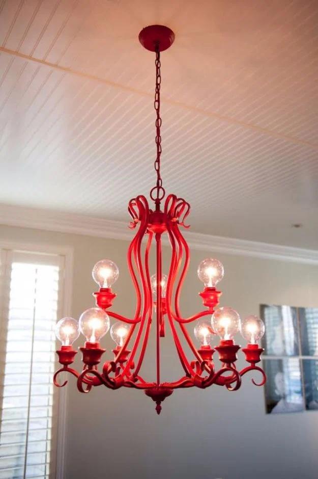 Chandelier makeover painted glossy red with clear exposed bulbs, hanging below a white beadboard ceiling