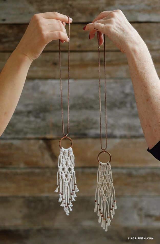 Simple DIY macrame necklace, two hands holding white knotted macrame fringe pendants on cords against weathered wood