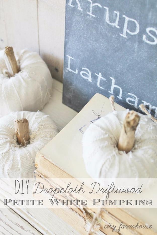 Small white fabric pumpkins made from wrapped drop cloth strips, finished with short driftwood stems