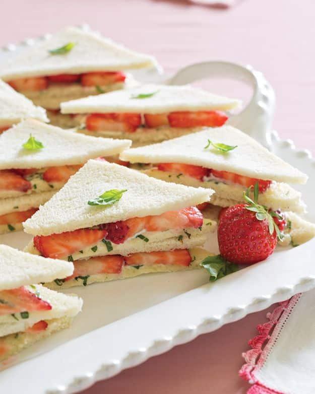 Strawberry tea sandwiches with basil cream cheese on thin white bread cut into triangles, a pretty warm weather snack idea