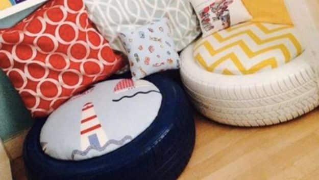 Two old tires covered in navy lighthouse print and yellow chevron outdoor fabric used as seats beside bright cushions