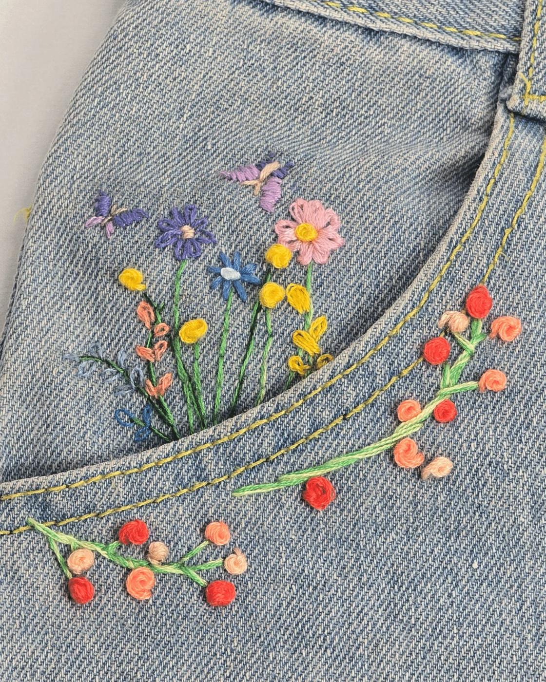 Step by step flower embroidery tutorial on denim, showing lazy daisy petals and French knot flower centers