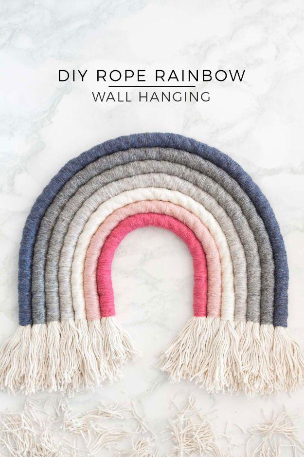 Rope rainbow wall hanging in navy, gray, pink and cream with fringed ends against a marble background