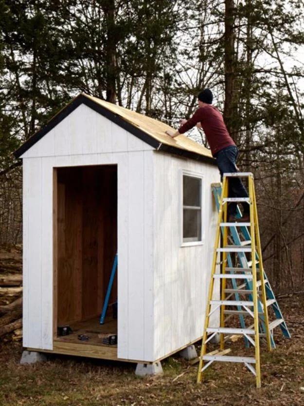 Simple shed from scratch, a white framed shed under construction in woodland with a stepladder standing at the open roof
