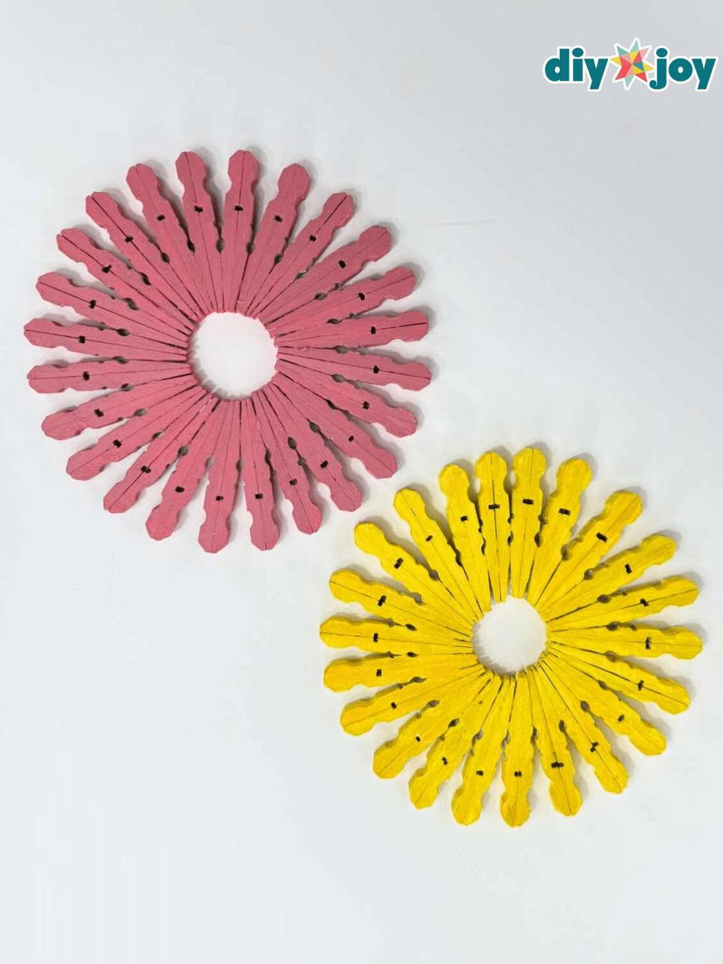 Pink and yellow sunburst trivets made from painted wooden clothespin halves glued in a ring on a white table