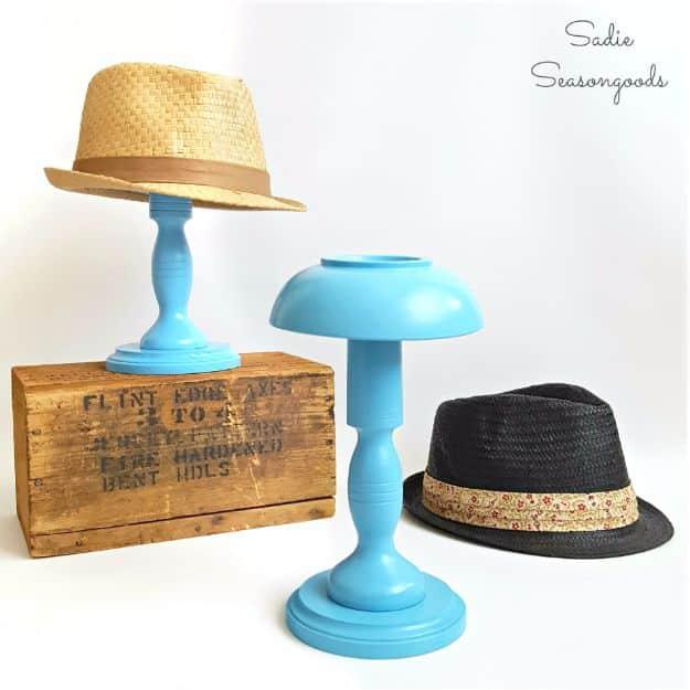 A turned wood hat stand stained dark, holding a straw hat on a hall table, primitive country craft in warm light