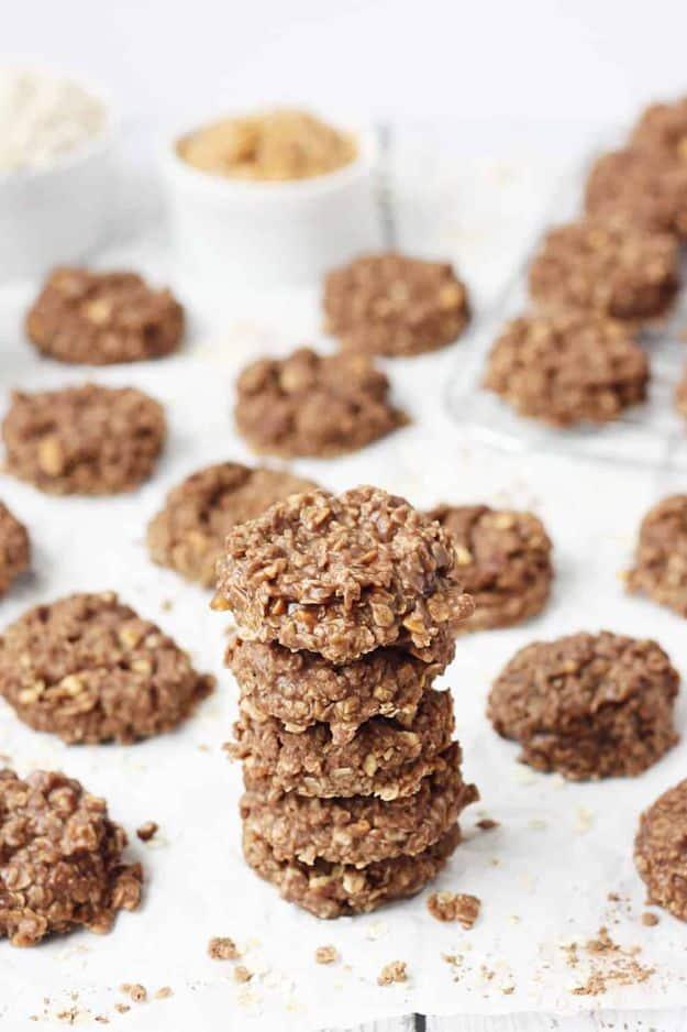 Crunchy peanut butter no bake cookies stacked in rows on parchment paper, set and glossy with oats visible
