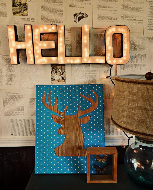 Lighted cardboard letters spelling HELLO glowing above a teal polka dot canvas with a wood grain deer