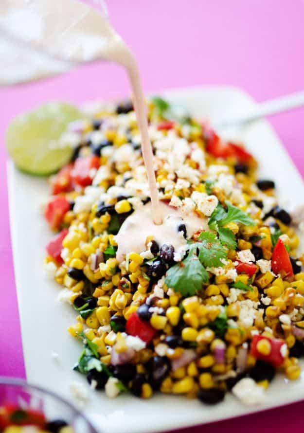 Mexican street corn salad with charred corn, black beans, red pepper and cotija, dressing poured over the top