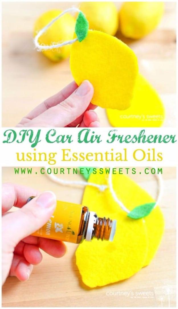Yellow felt lemons with green felt leaves on twine loops, held beside a bottle of essential oil and real lemons