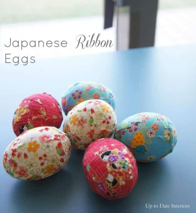 Six eggs wrapped in pink, red and pale blue Japanese patterned ribbon tape, on a blue table beside a window