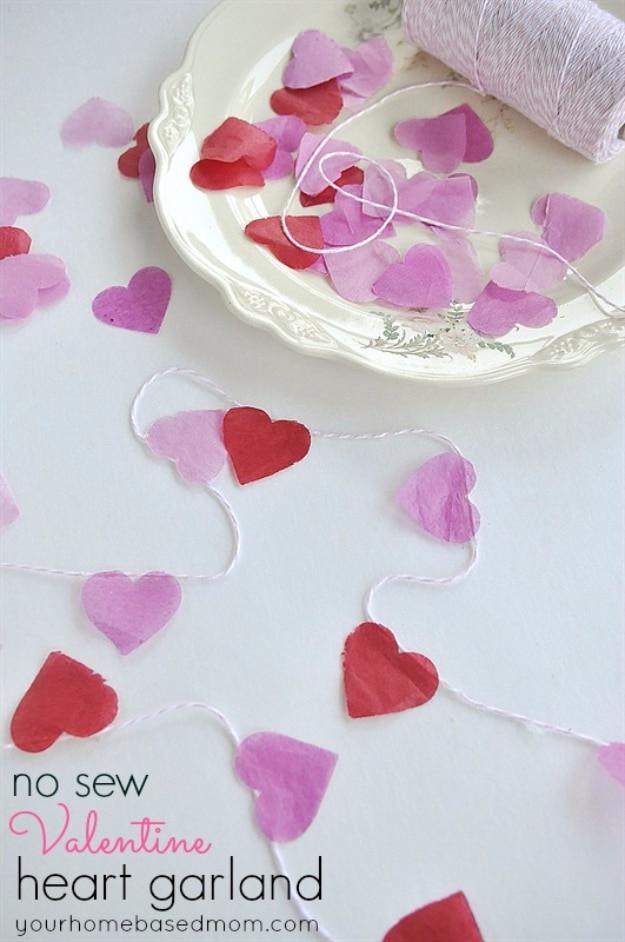 No sew fabric heart garland in pink and red strung along a ribbon across a white mantel for Valentine's
