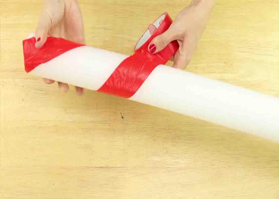Putting red tape to the pool noodle to make candy stripes