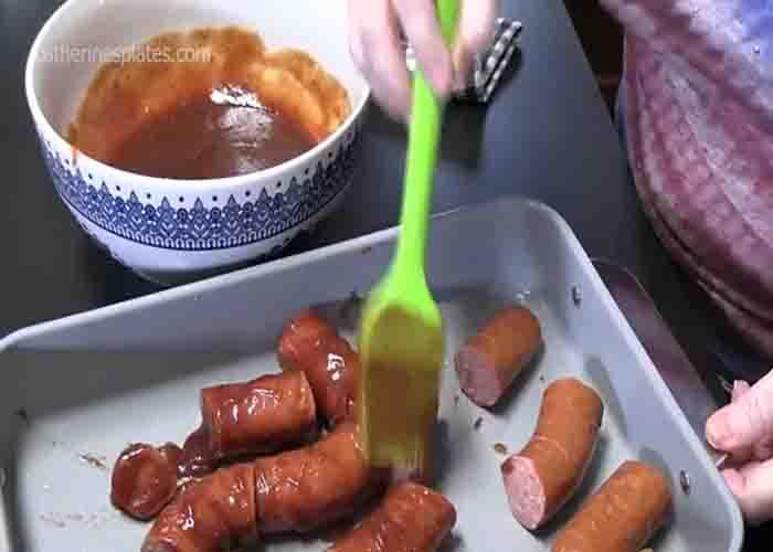 Slathering the hasselback sausages with barbecue sauce