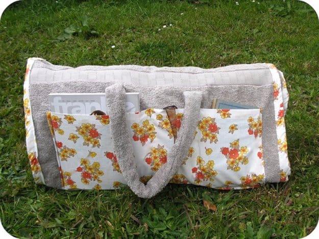 Beach towel tote sewing project to sell, a gray terry beach towel rolled up with floral patch pockets and terry handles