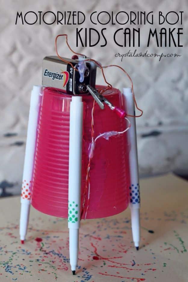 Motorized coloring machine, an upside down pink cup with three markers as legs and a battery on top, on scribbled paper