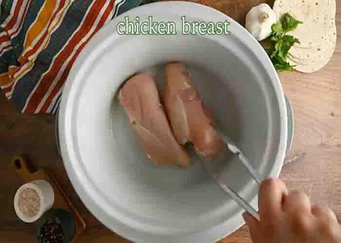 Adding the chicken breast to the slow cooker to make the tacos