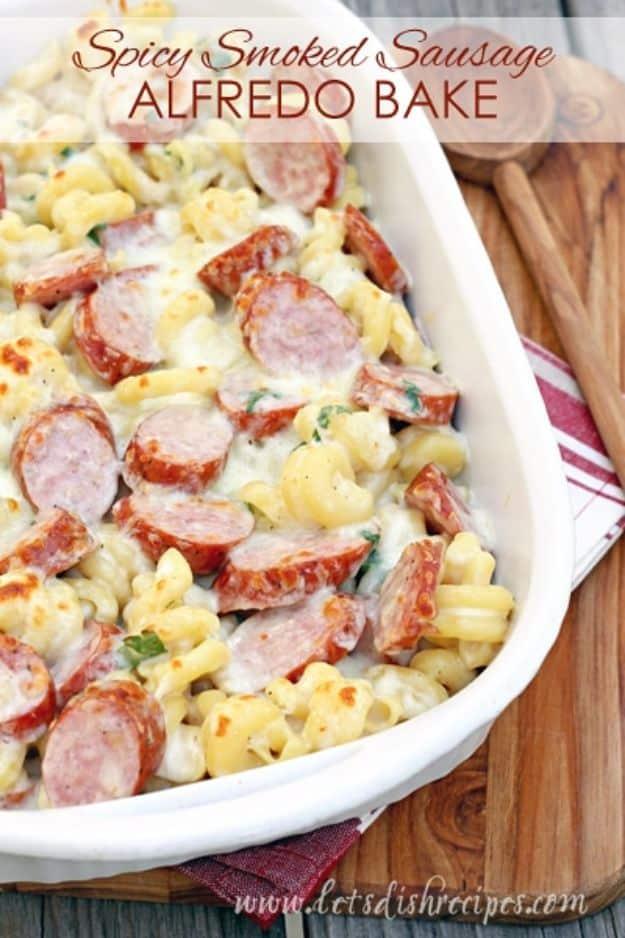 Spicy smoked sausage alfredo bake in a white dish with penne, sliced sausage and melted cheese on top