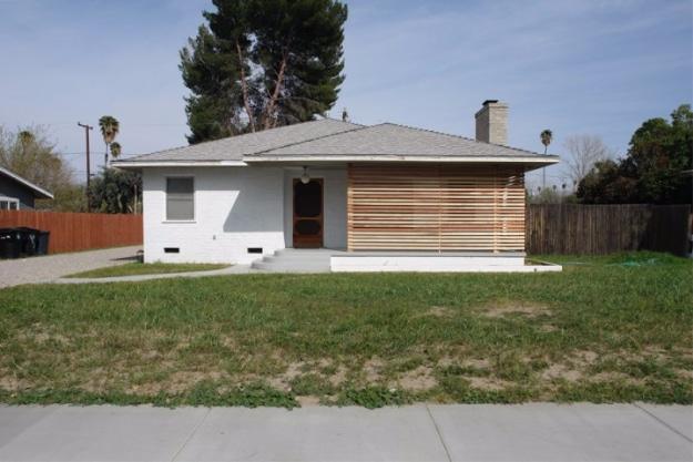 DIY curb appeal slat screen in horizontal natural wood across the front windows of a white stucco ranch style house