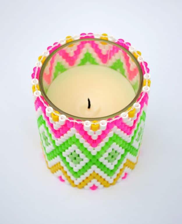 Perler bead candle holder, a woven neon pink green and yellow bead band around a lit glass candle jar