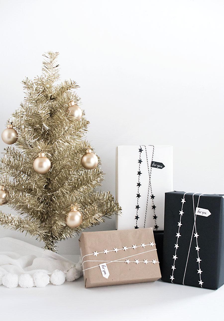 White, kraft and black wrapped parcels strung with paper star garlands and small for you pennant tags