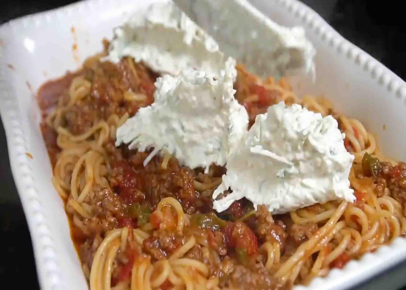 Assembling the baked spaghetti into a casserole dish