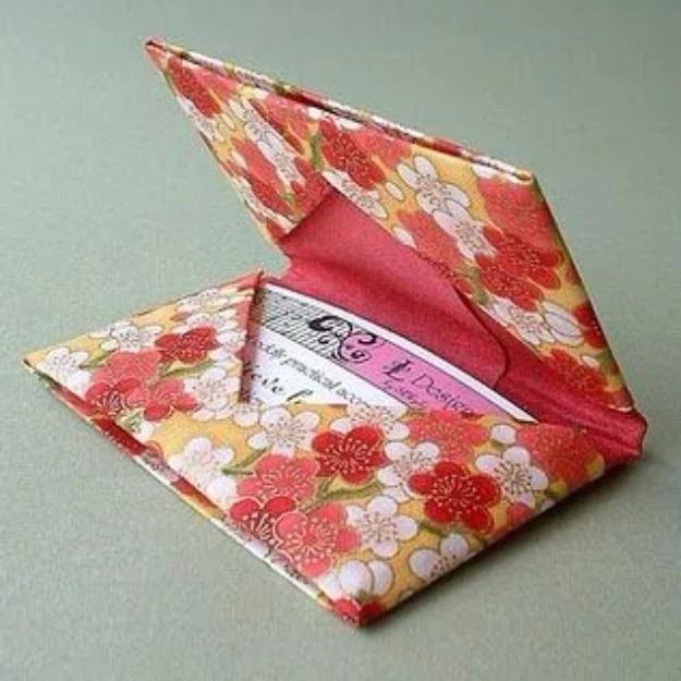 Origami card holder folded from red and gold cherry blossom wrapping paper, opened to show a card inside