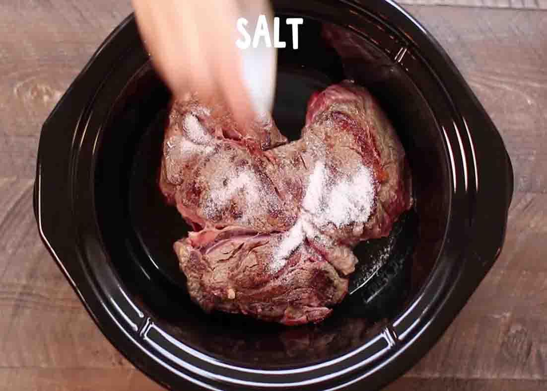 Seasoning the beef chuck roast in the slow cooker