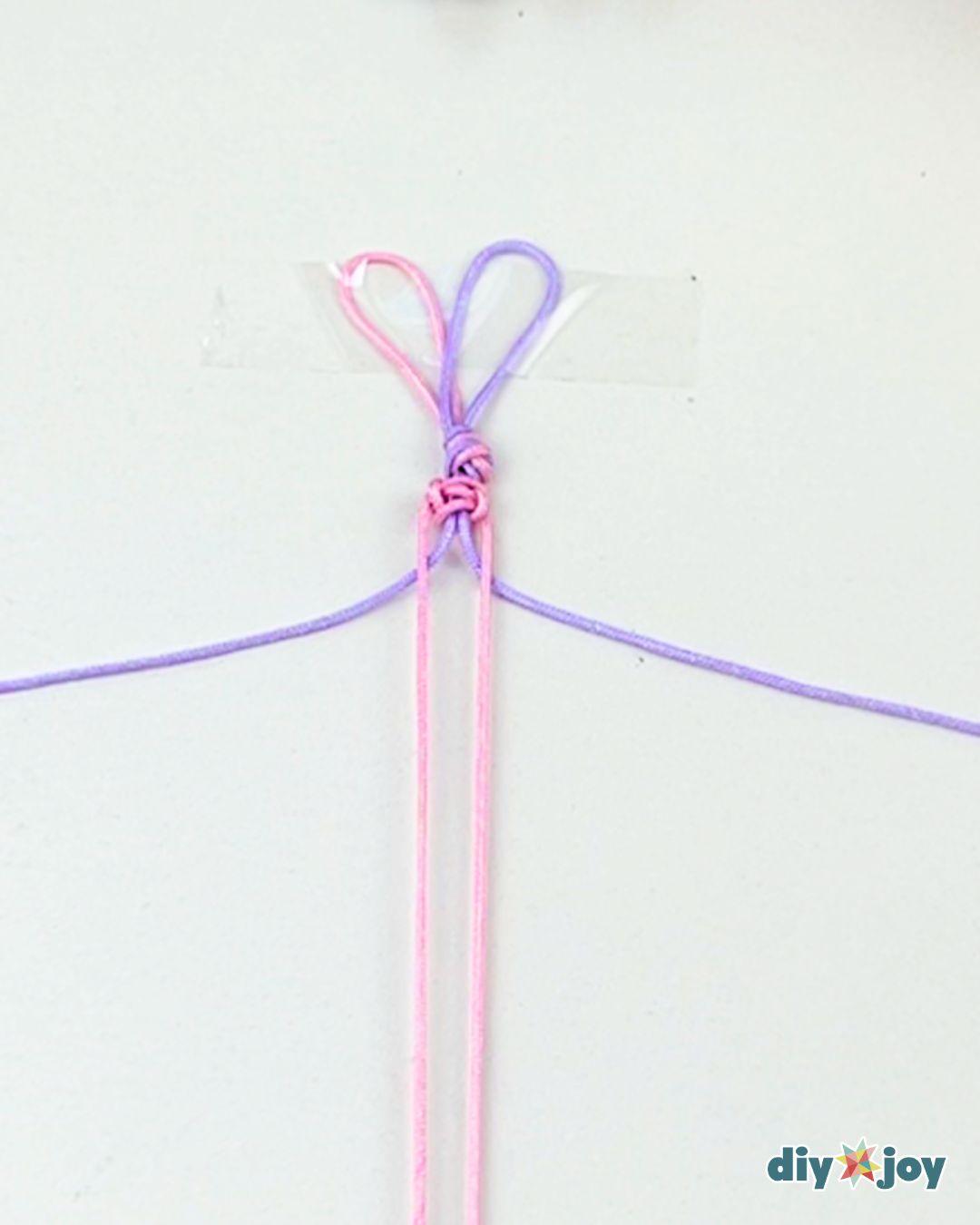 A macrame bracelet growing longer on the table, the knotted band measured against a wrist to check for length