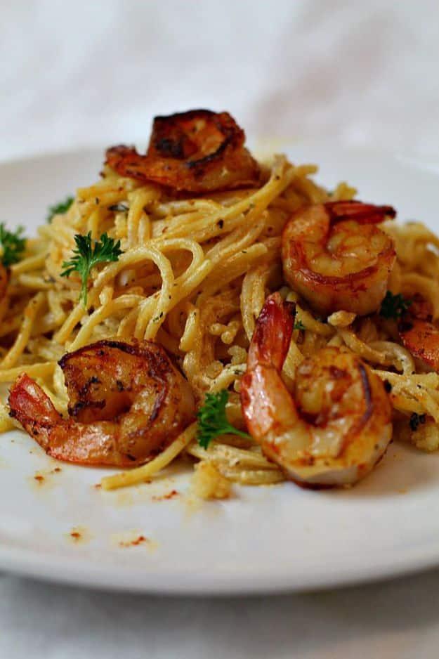 Spicy creamy shrimp pasta on a white plate, linguine in a pale sauce topped with seasoned shrimp and parsley