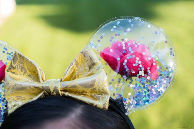 Enchanted rose Mickey ears headband with clear domed ears holding red roses and glitter and a gold bow