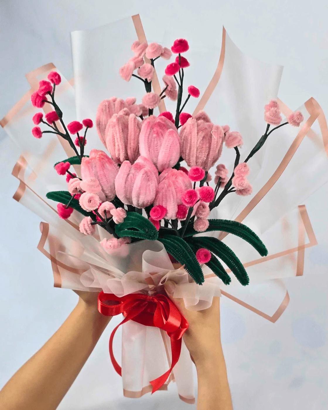 A pink pipe cleaner flower bouquet combining handmade tulips and baby's breath in a vase for spring decorating