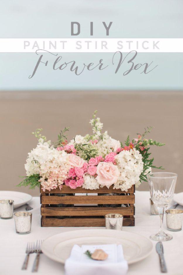 Wooden slat crate filled with blush and white flowers on a set table with glasses, under a typeset title band