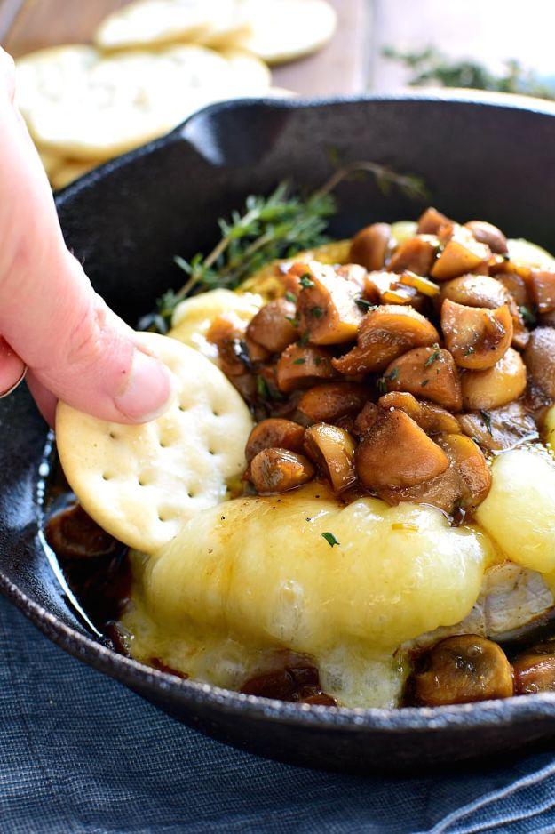 Mushroom marsala baked brie in a small cast iron skillet topped with browned mushrooms and fresh thyme