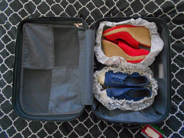 Reuse an old shower cap as a shoe cover, two pairs of shoes bagged in clear caps inside an open suitcase